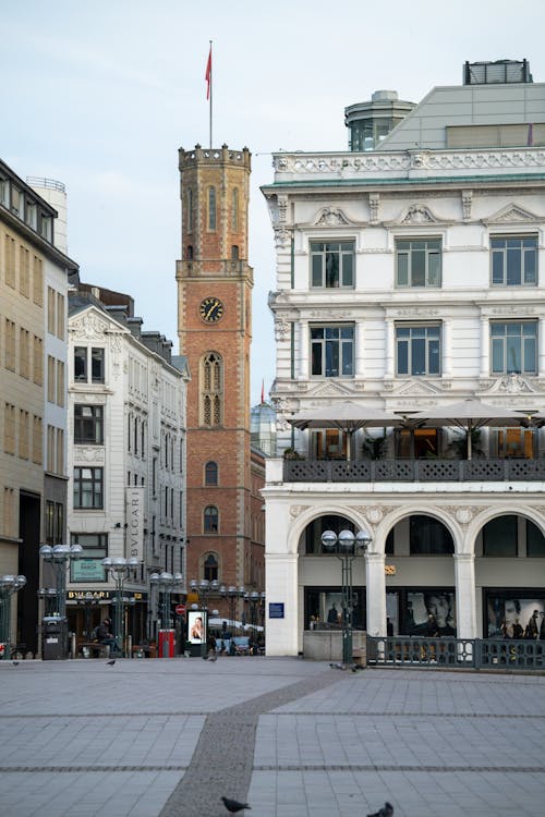 Paved square with aged buildings and brick tower in city of Hamburg in Germany
