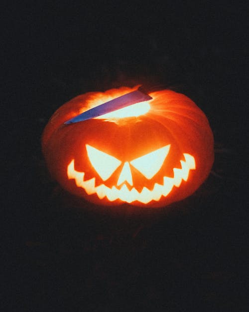 Shiny carved pumpkin and knife on Halloween night