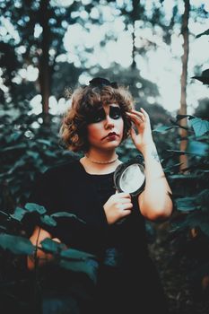 一位化着浓妆的年轻女子拿着镜子，站在幽灵般的森林里