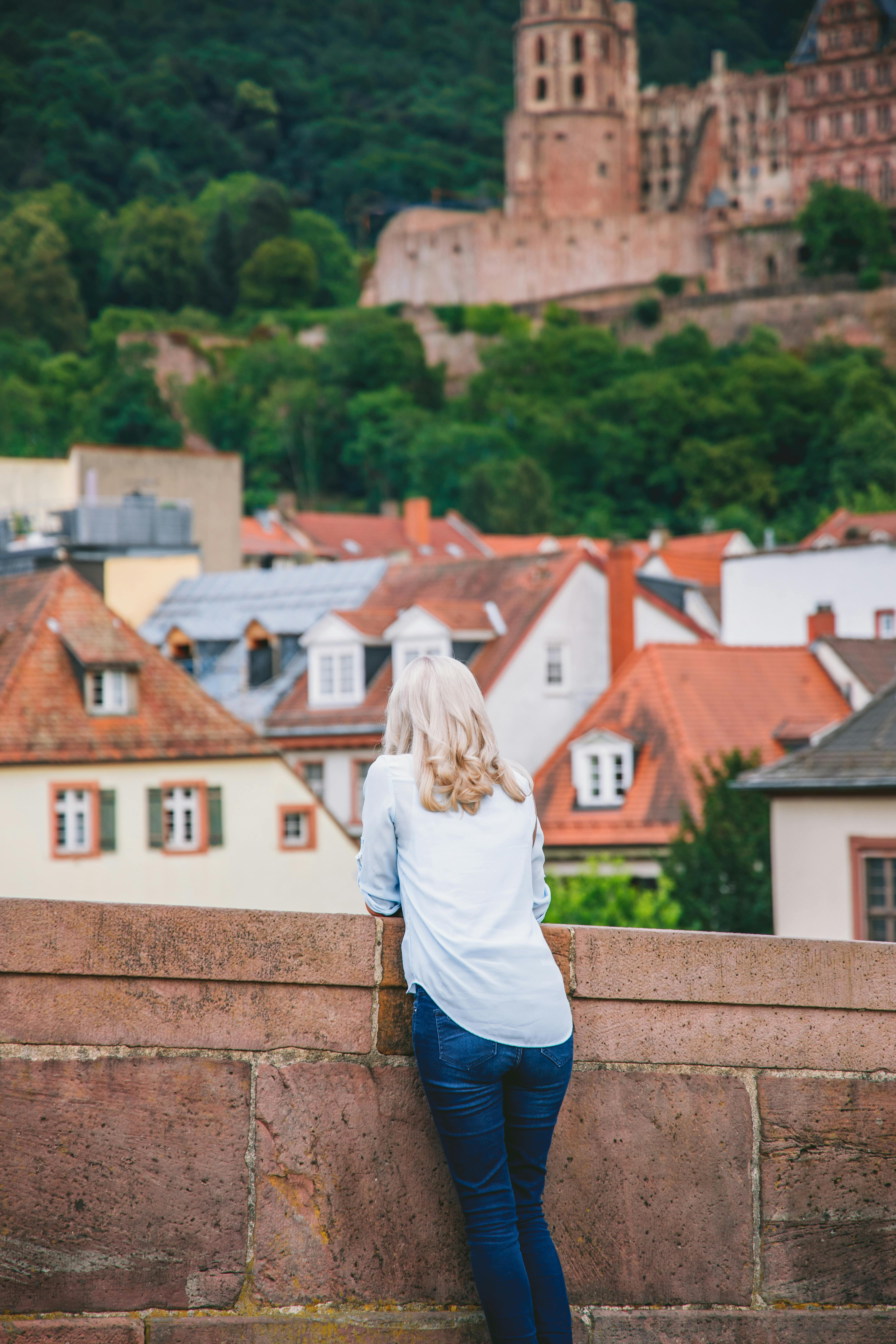 Woman in White Long Sleeve Shirt and Blue Denim Jeans Standing on Roof Top