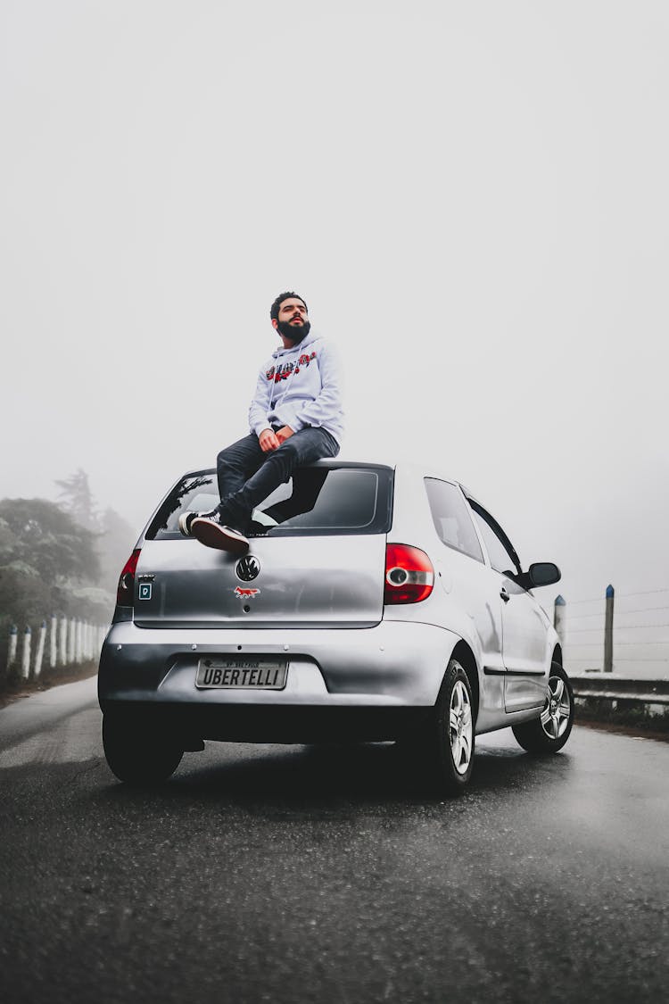 Stylish Dreamy Hipster Man Resting On Car Under White Sky