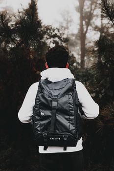 一名男性背包客在雾蒙蒙的秋季林地中探索，捕捉冒险与旅行的本质