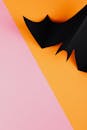 黑色纸蝙蝠在充满活力的粉色和橙色背景上，非常适合万圣节主题