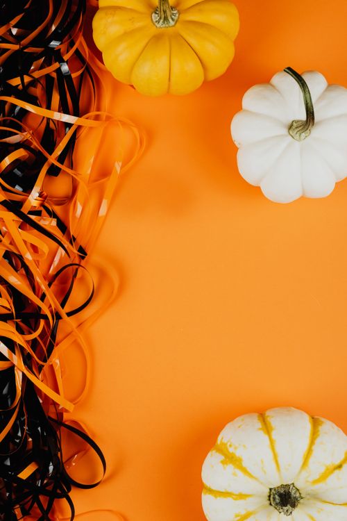 Free Festive Halloween arrangement with colorful pumpkins and ribbons on an orange background. Stock Photo