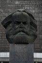 Stone head sculpture of revolutionary placed on high postament against stone wall in city