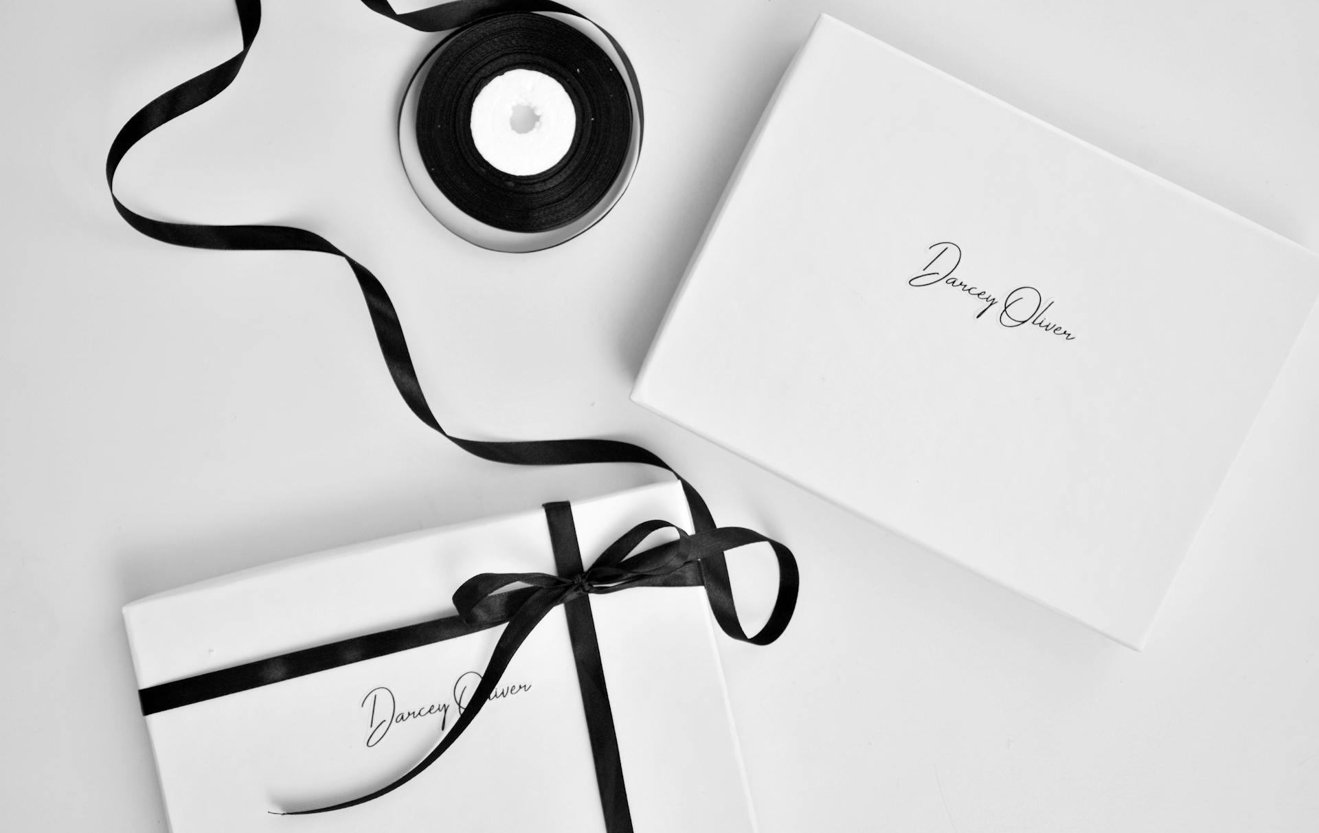 Top view of similar white boxes with inscriptions on table near black rolled ribbon