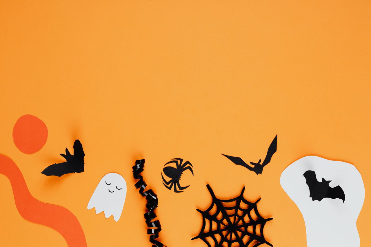 paper cutouts of bats ghosts and spiders on an orange background creat