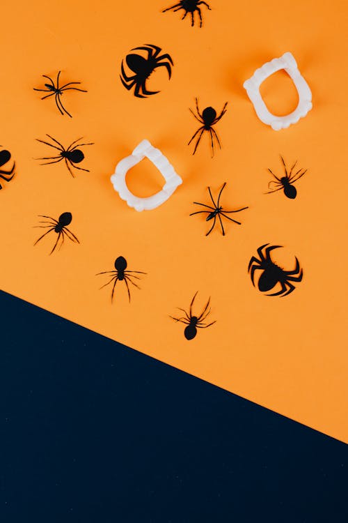 Black Paper Spiders and Vampire Fangs on Orange Background