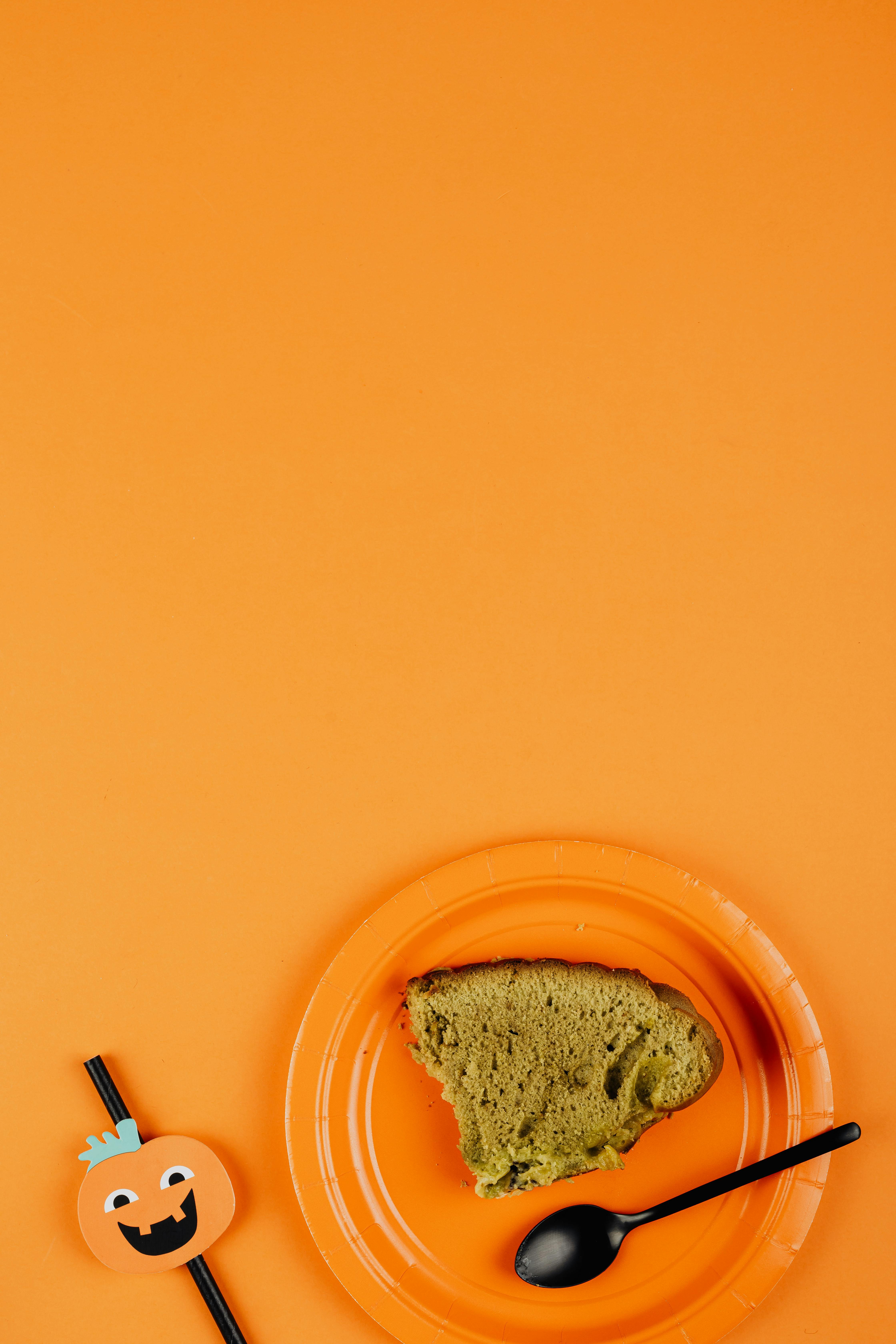 绿色蛋糕片放在装饰有万圣节图案的橙色盘子上