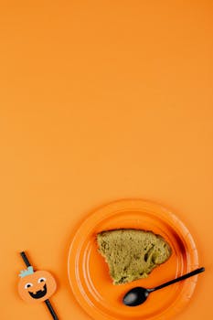 绿色蛋糕片放在装饰有万圣节图案的橙色盘子上