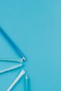 White and Blue Plastic Sticks on Teal Surface