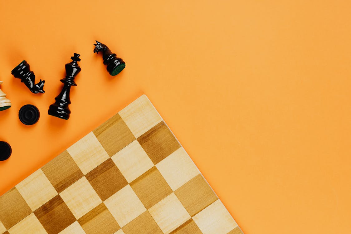 Chess Board and Black Chess Pieces Beside on Yellow Background · Free Stock  Photo