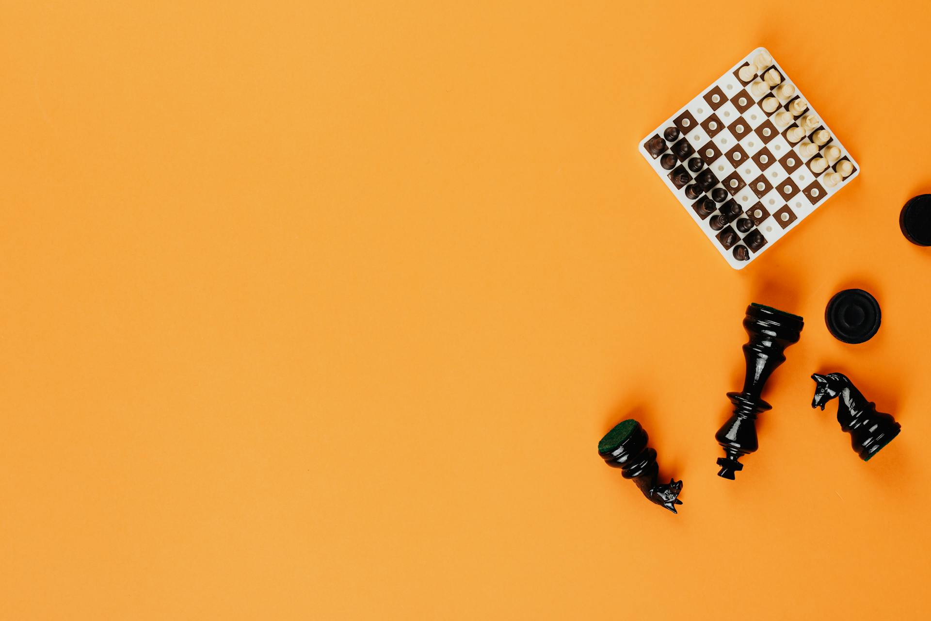 Miniature Chess Board and Black Chess Pieces on Yellow Background