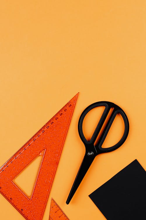 Red Ruler and Black Scissors on Yellow Background