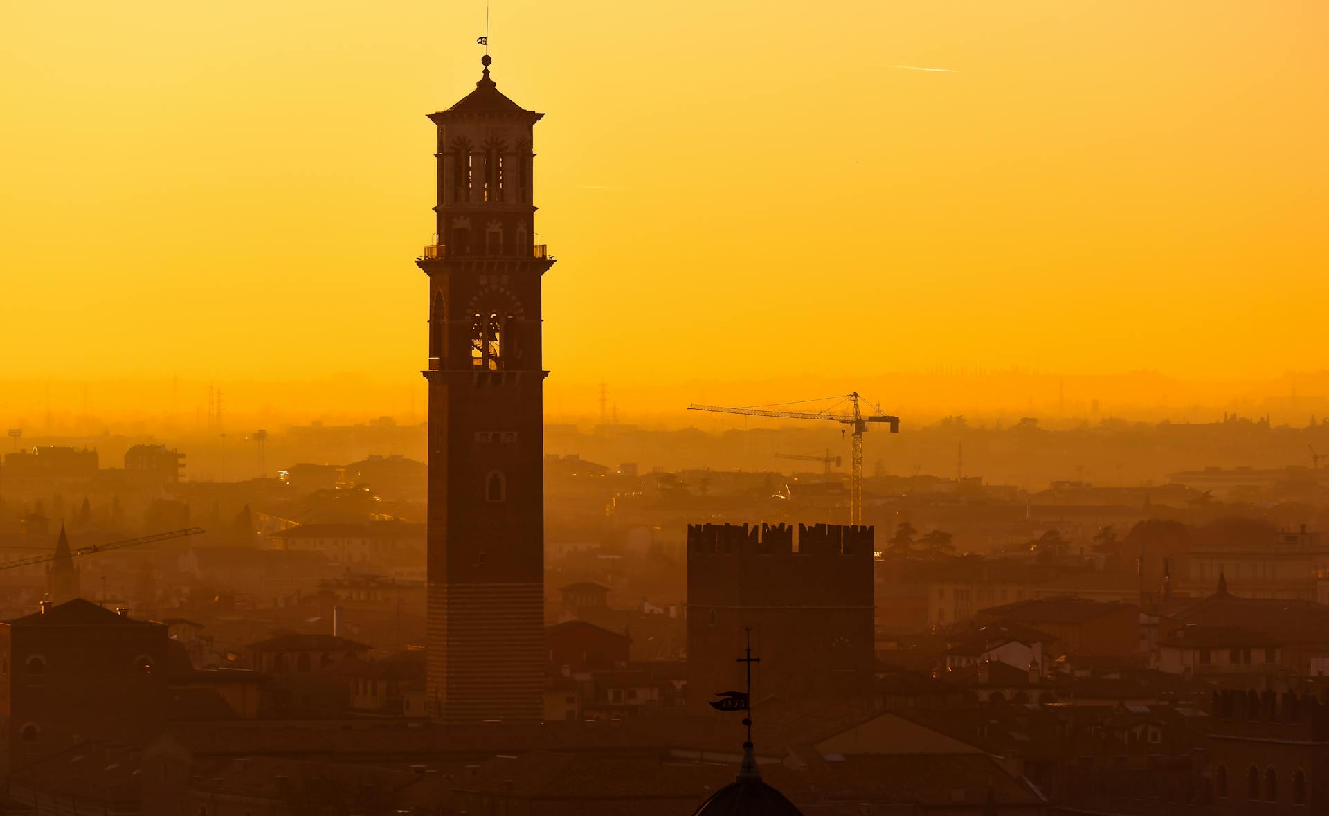 Silhouette of Torre dei Lamberti with a breathtaking sunset over Verona, Italy's cityscape.