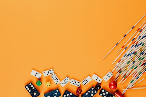 Free Dominoes and Wooden Sticks over Orange Surface Stock Photo