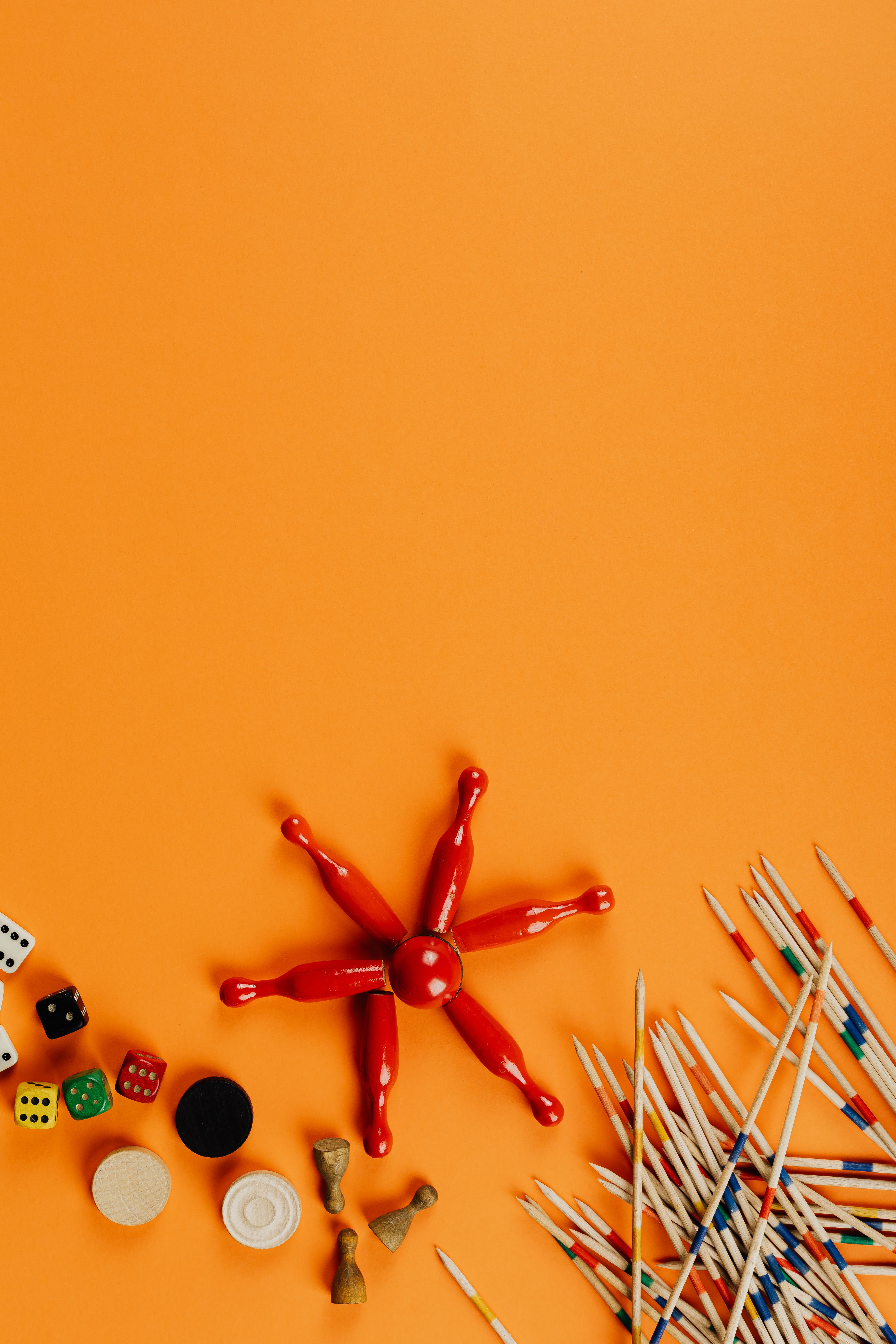 Flat lay of assorted board game pieces against a vibrant orange background, perfect for gaming themes.
