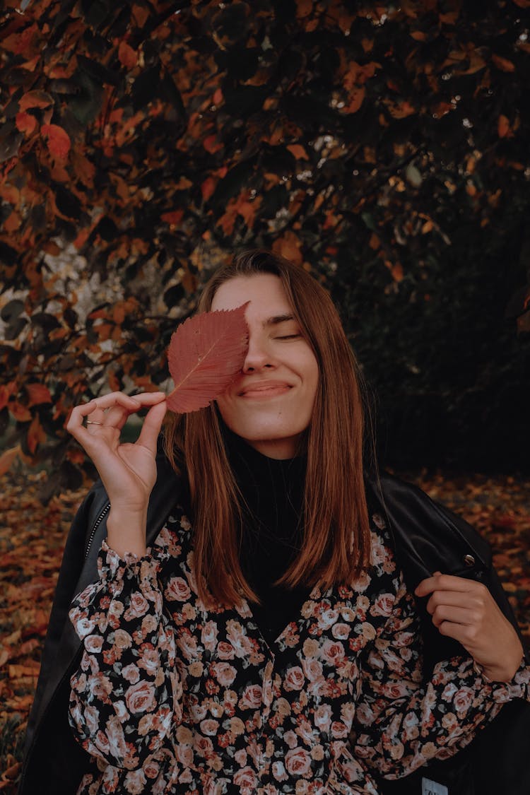 A Woman Holding A Leaf Covering Her One Eye