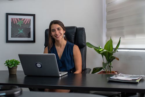 Free A Smiling Woman Sitting on a Black Leather Chair Stock Photo