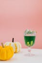 粉红色背景旁，点缀着糖果的黄色南瓜旁，是一杯充满活力的绿色饮料
