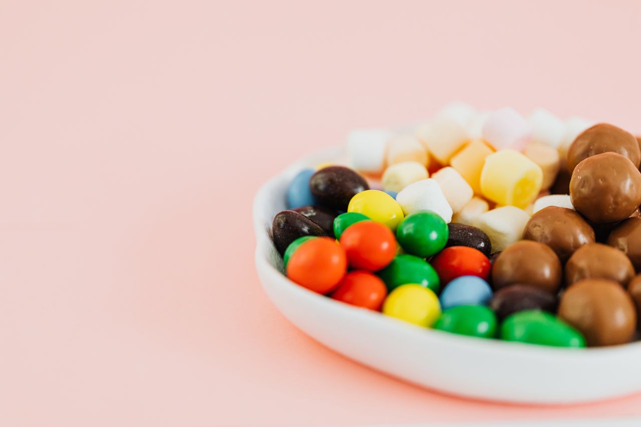 a colorful assortment of candies in a white bowl featuring chocolates
