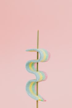 在粉红色背景下，彩色果冻糖果插在棍子上，于工作室灯光下拍摄