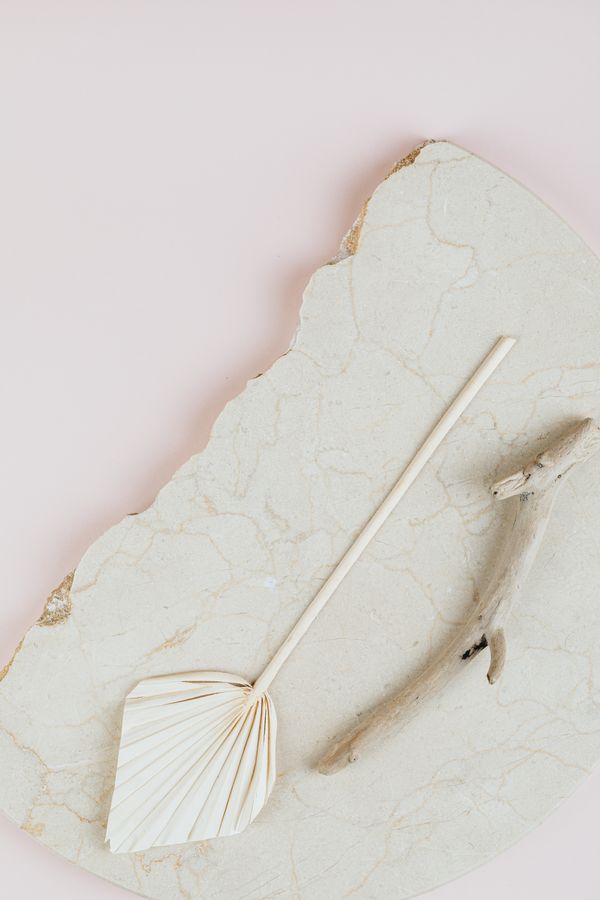 Folded palm-leaf hand fan on a stone slab — photo by Kaboompics on Pexels