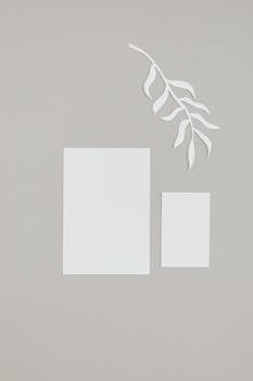 灰色背景上，白色纸张与树叶剪纸构成抽象设计