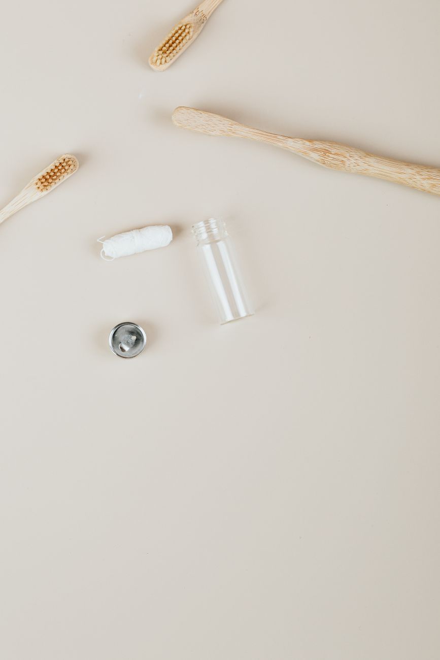 Top view of dental floss and bamboo toothbrushes on a plain surface