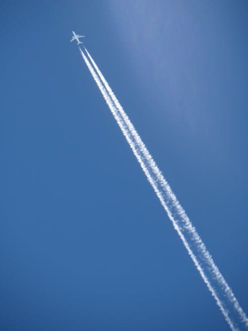 grátis Foto profissional grátis de aeronave, céu azul, esteiras de fumaça Foto profissional