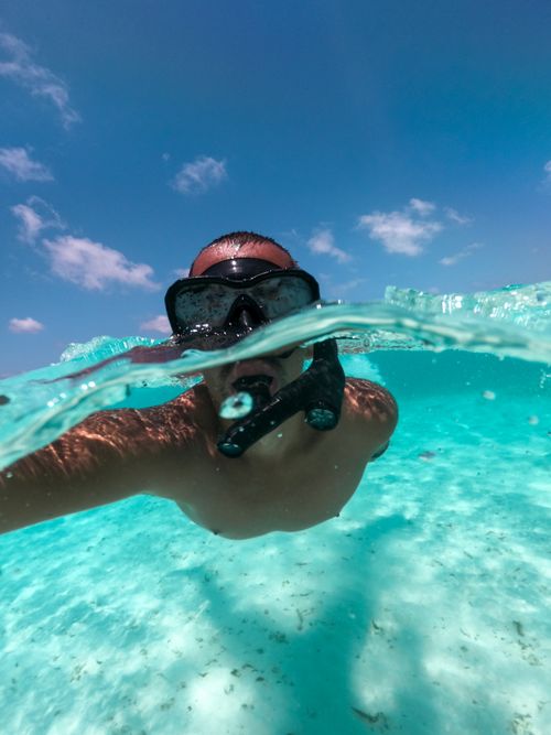 Free Person snorkeling in clear blue water on a sunny day, capturing an underwater view. Stock Photo
