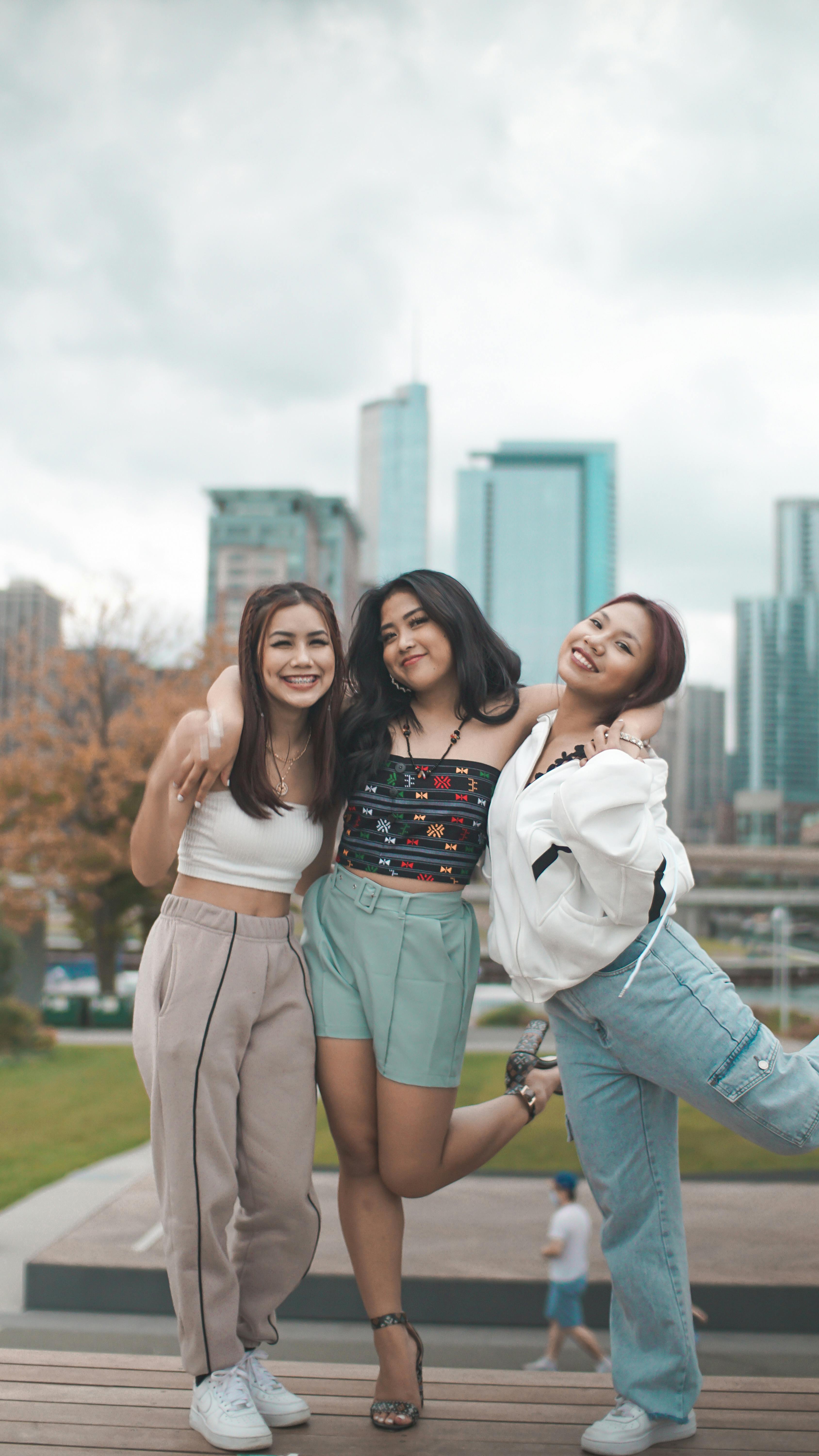 Three teenagers enjoying a day outdoors in a city park, smiling and posing together.
