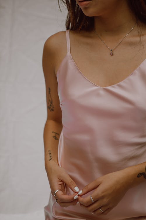 Faceless alluring lady in silk top against white background