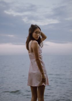 黄昏时分，一名年轻女子平静地站在海边，营造出宁静的氛围