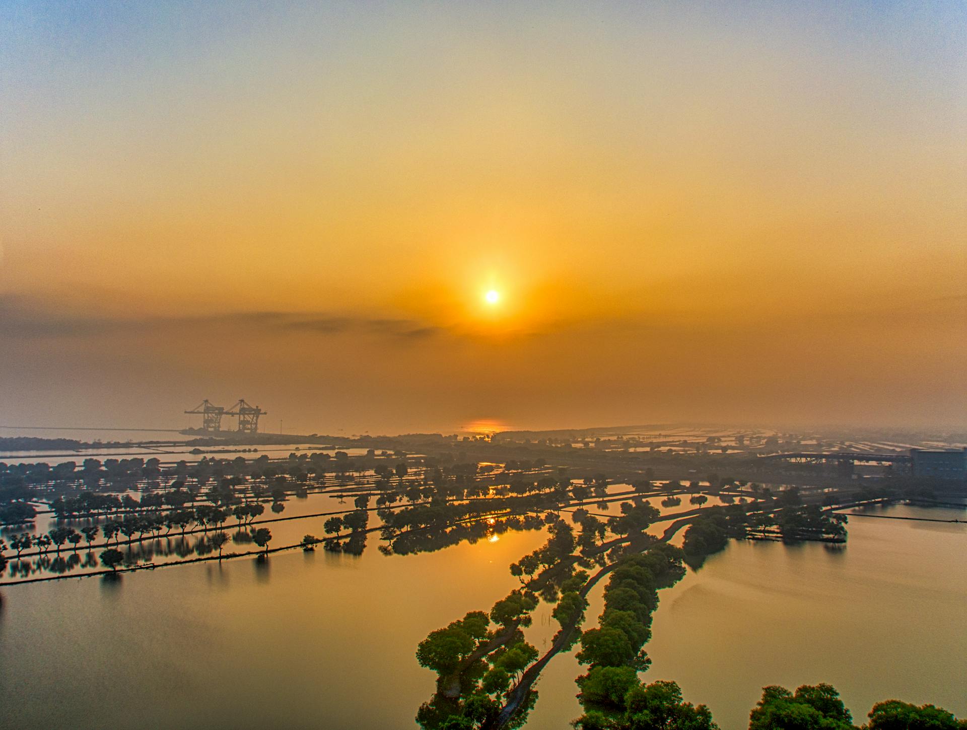 Serene aerial view capturing the sunset over lush, flooded landscapes with tranquil canals.