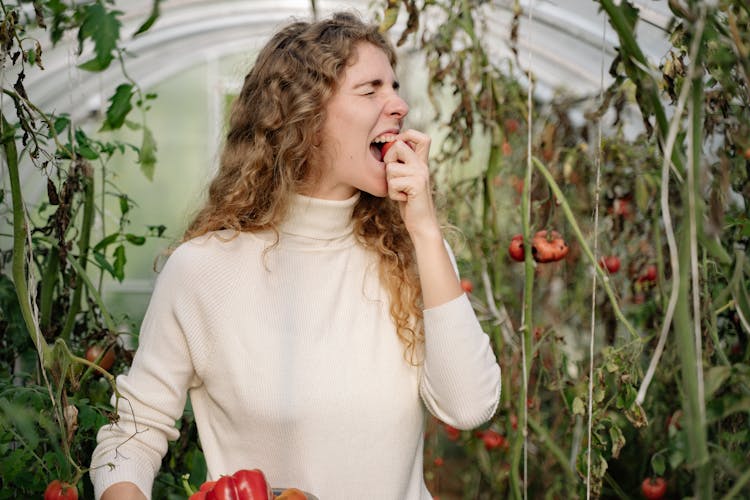 A Woman Eating A Red Fruit