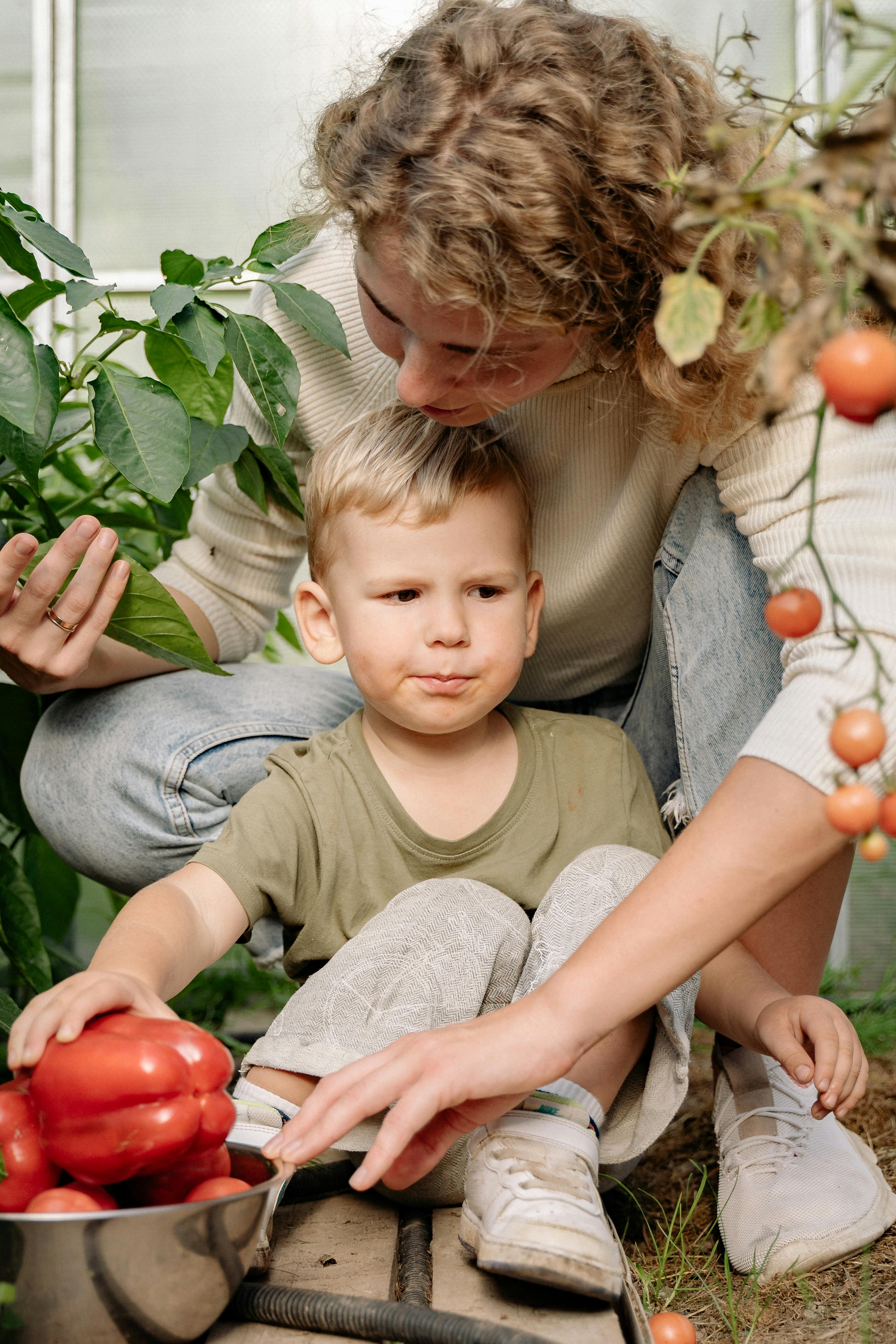 a woman harvesting fresh vegetable with a boy