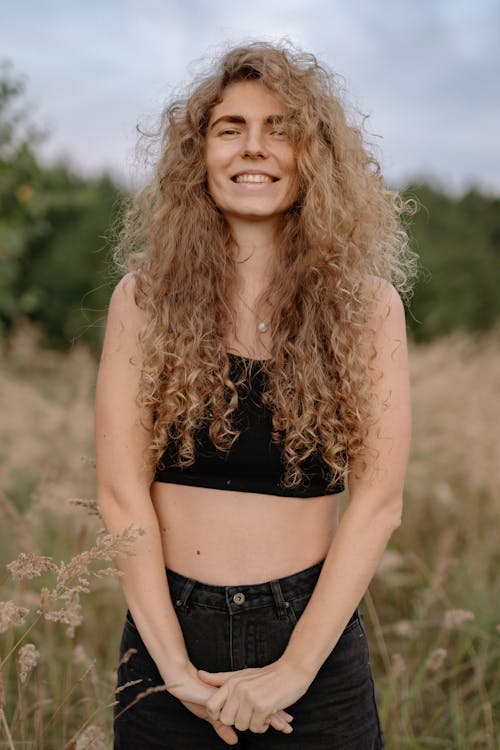 A Woman in Black Crop Top Standing in the Grass Field