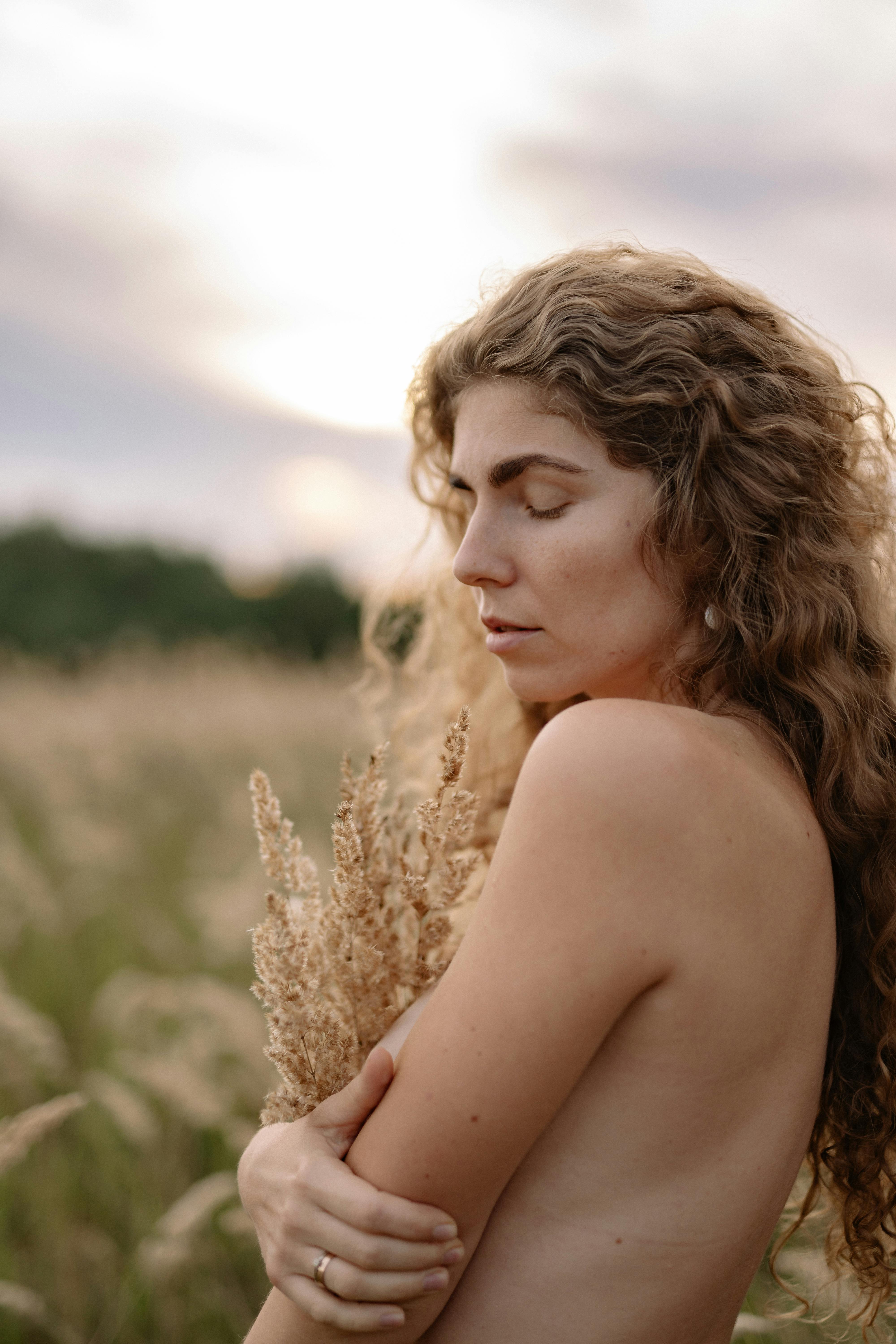 portrait of a shirtless woman with dry grass