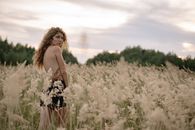 Woman in Black and White Floral Spaghetti Strap Dress Standing on Green Grass Field