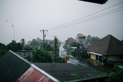 Free A serene view of an Indonesian village street during a rainy day, showcasing local architecture. Stock Photo