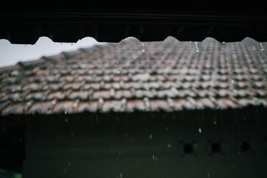 雨点飘落在瓷砖屋顶的特写镜头里，捕捉到了雨天那喜怒无常的氛围