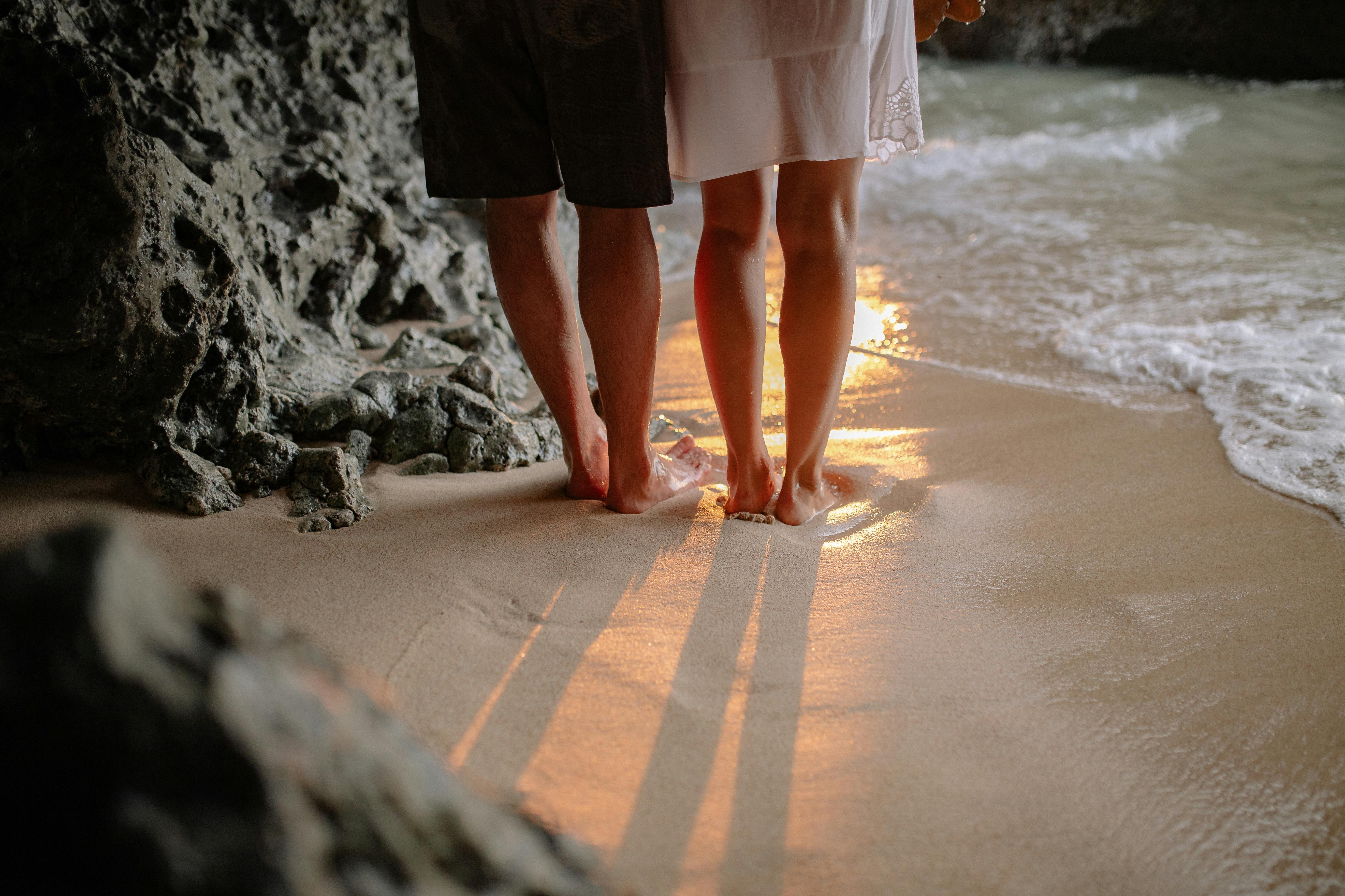 日落时分沙滩上情侣双腿剪影，凸显浪漫与宁静