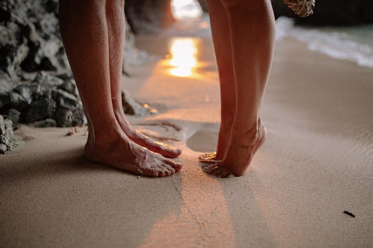 Close-up Of Couple Legs On Beach