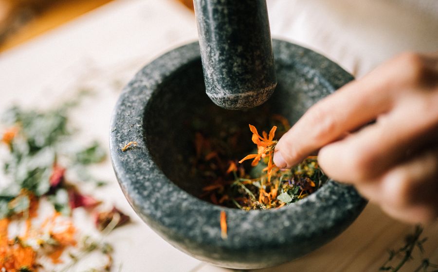 Ayurveda and Panch Karma in Mumbra with herbs being prepared in a stone mortar for traditional wellness use