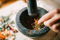 将充满活力的香草在石钵中用手压碎，混合天然成分