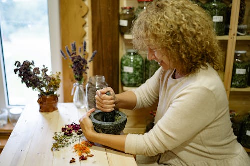 A Woman Grinding Petals with Mortar and Pestle