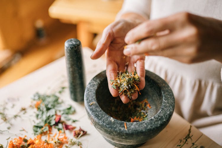 Close-up Of Woman Preparing Herbs In Pounder