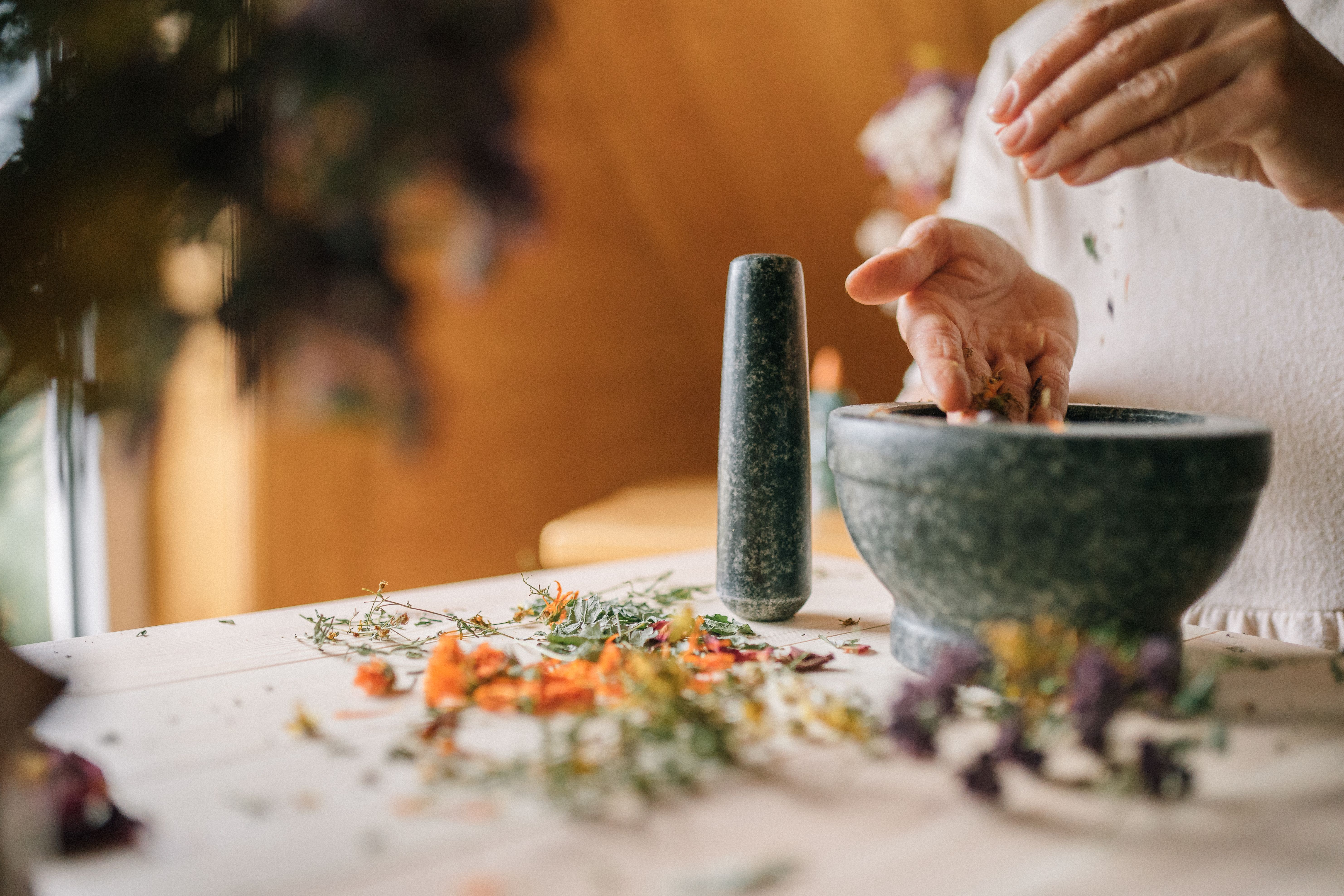 双手特写：在桌子上用迫击炮和槌准备草药