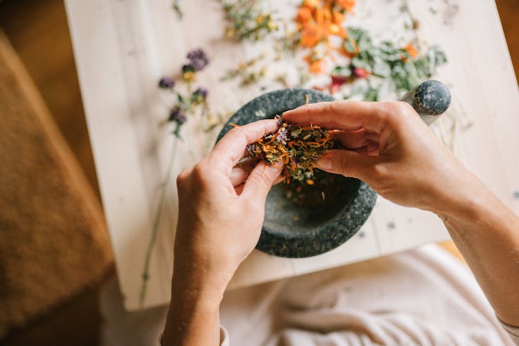 Top View Of Woman Mixing Herbs In Mortar